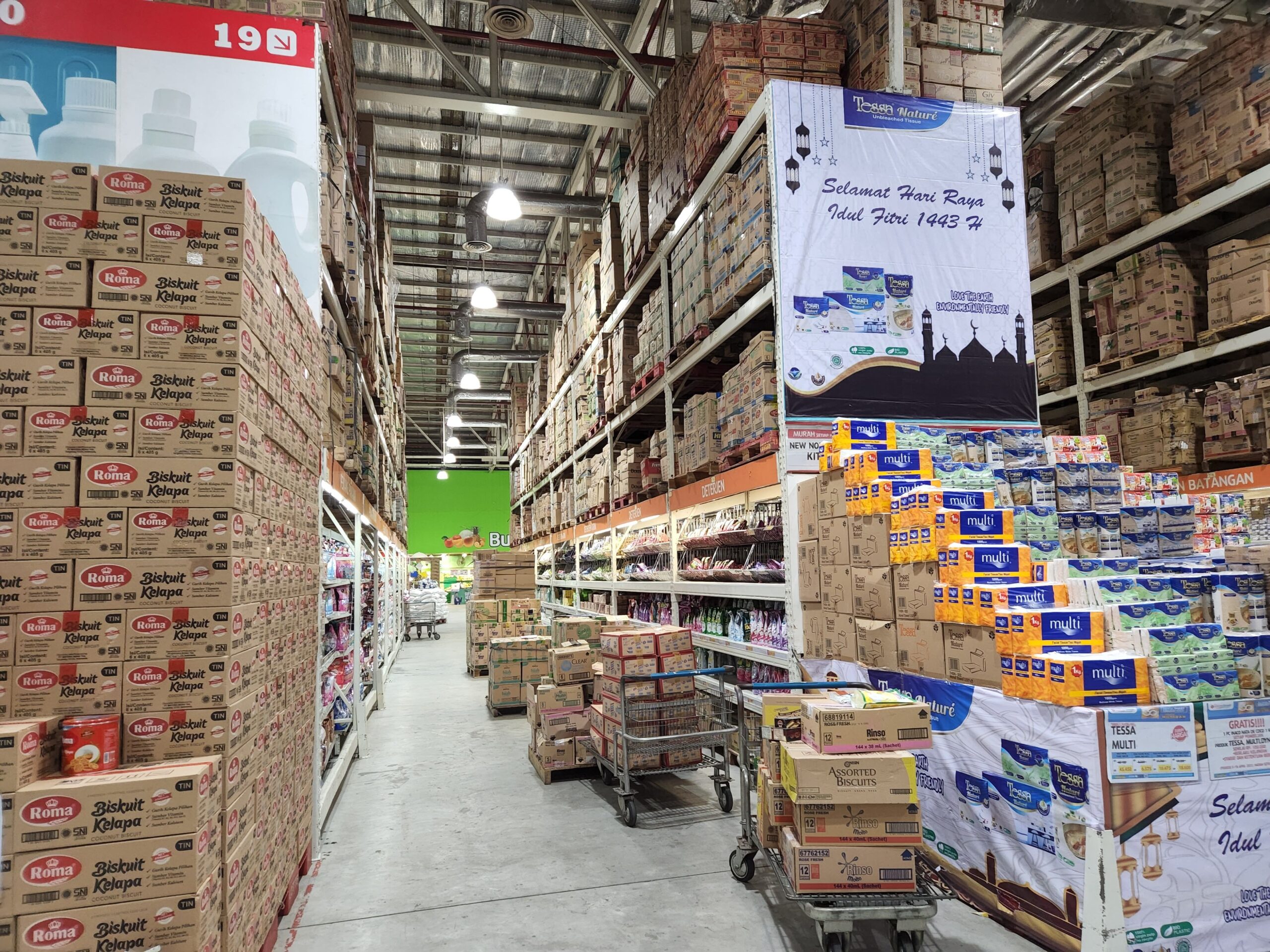 High shelves in a warehouse stocked with a variety of merchandise and large cardboard boxes.